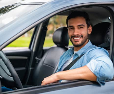 Man smiling on board his car.