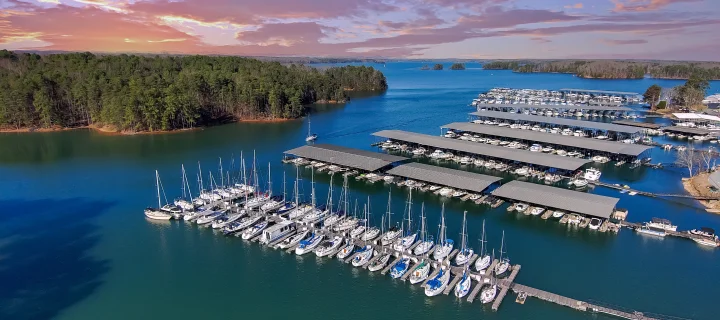 Boats and yachts docked and sailing in the marina on Lake Lanier with lush green trees and clouds at sunset: Cheap car insurance in Gainesville, Georgia.