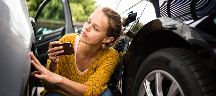 Pretty, young woman checking the state of a car for insurance purposes, prior to start driving it after renting it from a car rental. Automotive damage.