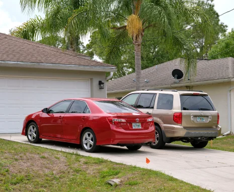 Car parked in front of wide garage double door on concrete driveway of new modern American house.